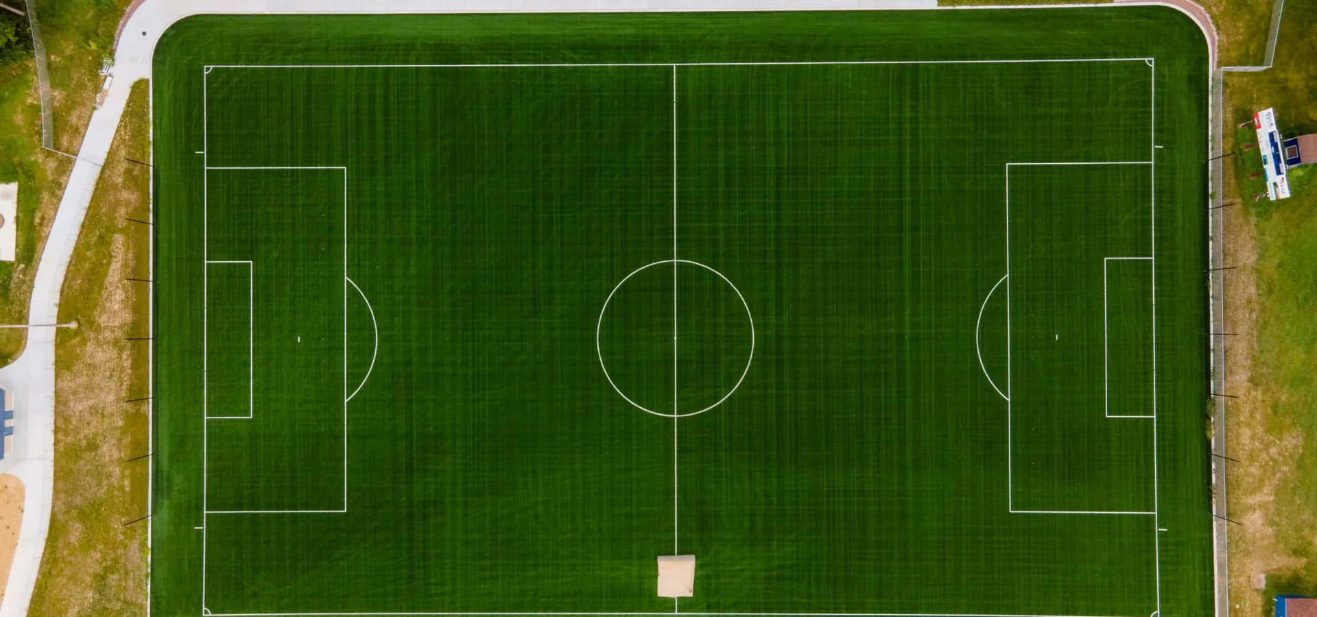 Vista aérea de una cancha de fútbol de pasto sintético rodeada por una pista de atletismo