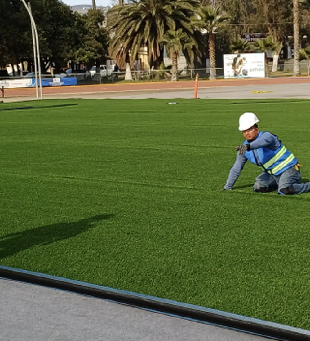 Instalador colocando pasto sintético en una cancha deportiva