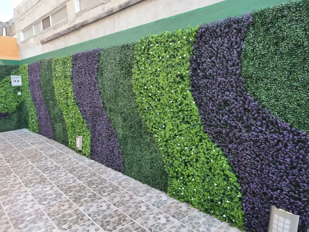 Muro verde artificial de gran superficie con diseño de ondas en dos tonos de verde y morado