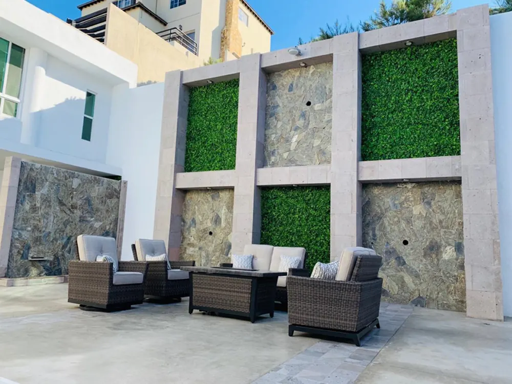 Paneles de follaje artificial entre columnas de piedra en la fachada de una casa