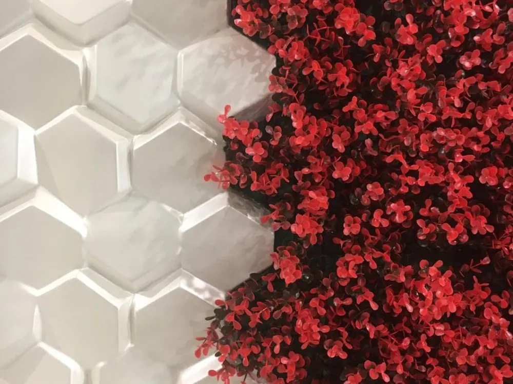 Detalle del follaje artificial rojo y verde sobre paneles hexagonales