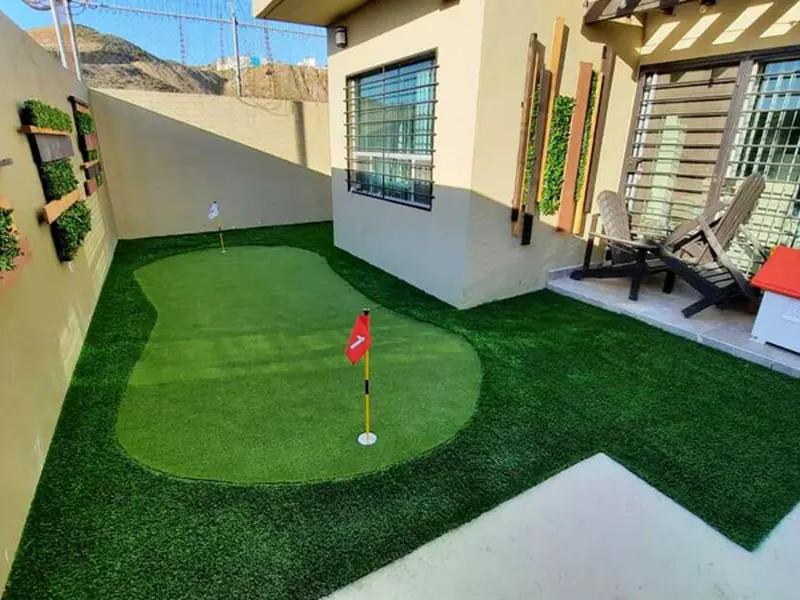 Putting green de pasto sintético en el patio de una casa