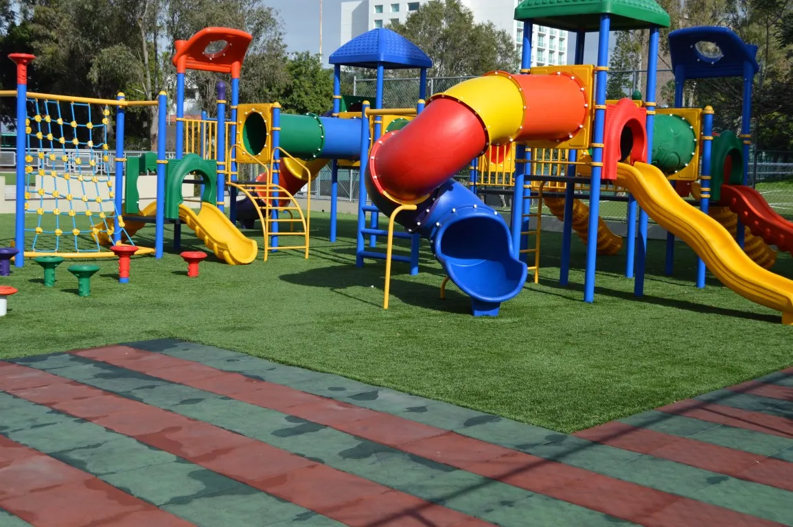Juegos infantiles sobre pasto sintético y loseta de caucho