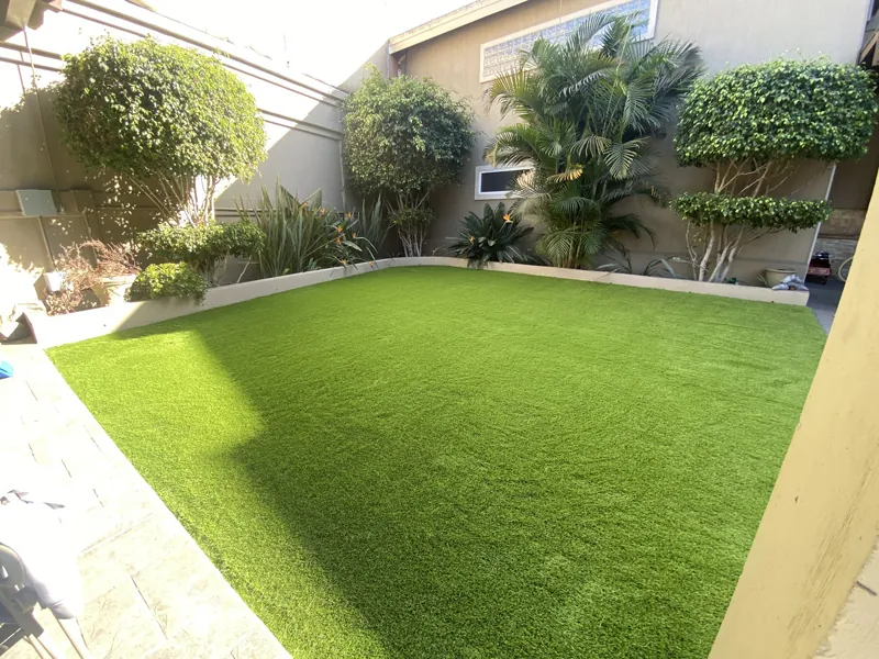 Jardín con pasto sintético rodeado de setos recortados