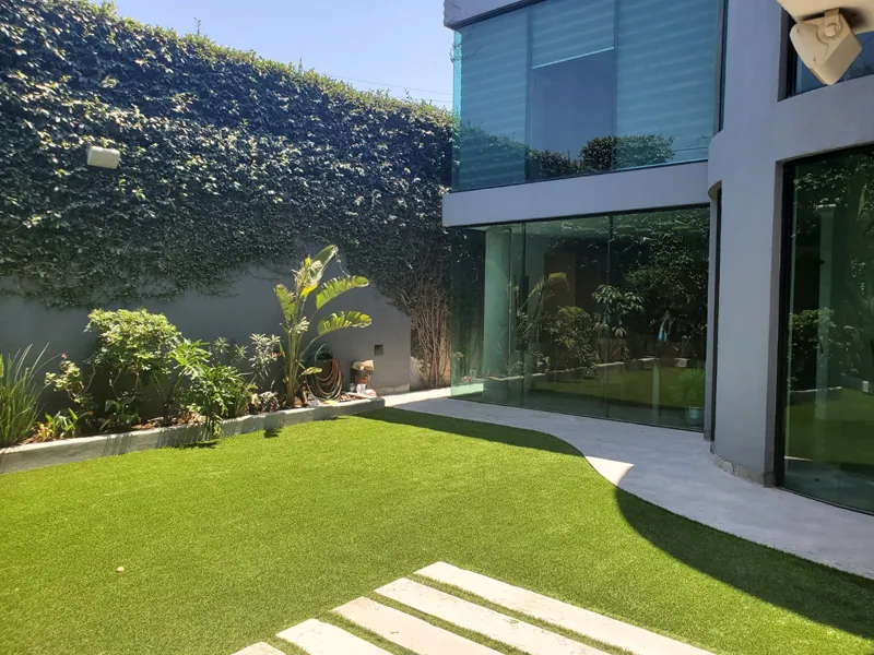 Jardín de casa moderna con pasto sintético y muro verde