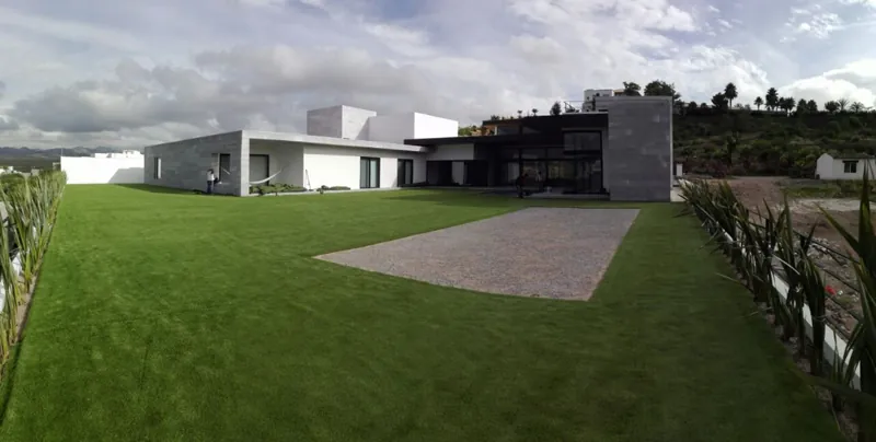 Jardín residencial amplio con pasto sintético y andador
