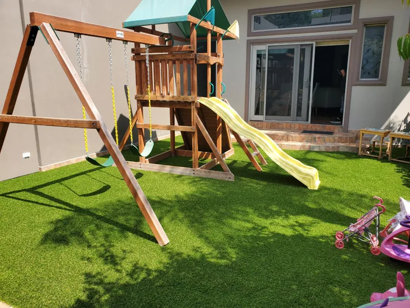 Juegos infantiles de madera con resbaladilla sobre pasto sintético