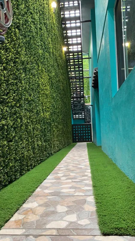 Pasillo con muro verde artificial, camino de laja y pasto sintético