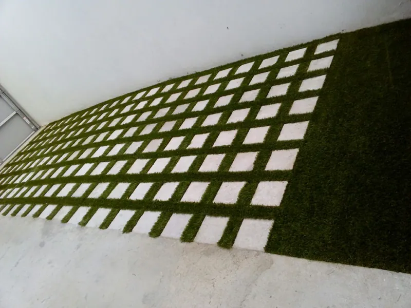 Losetas cuadradas con tiras de pasto sintético entre las juntas