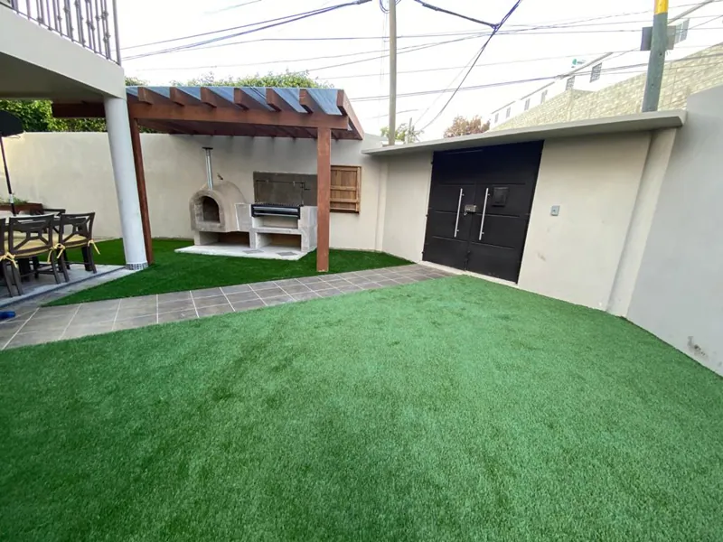 Patio con asador, techumbre y pasto sintético