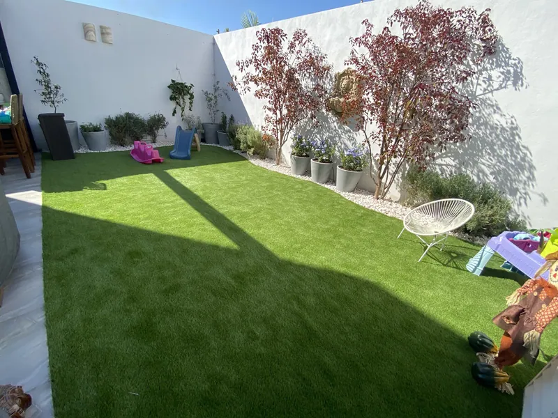 Patio de casa con pasto sintético y juegos de niños
