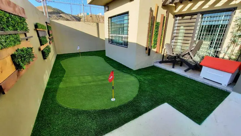 Putting green de pasto sintético corto en el patio de una casa