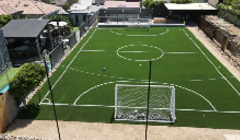 Cancha de fútbol de pasto sintético en el jardín de una residencia, vista desde lo alto