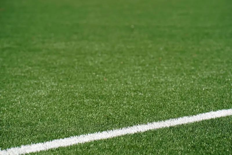 Línea blanca sobre el pasto sintético de una cancha de fútbol