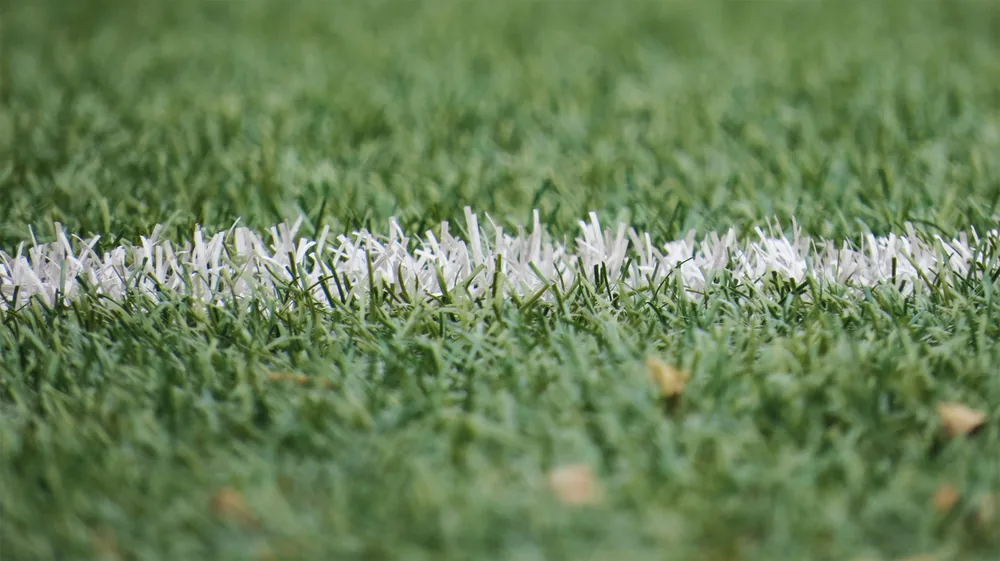 Línea blanca integrada en el pasto sintético de una cancha, vista de cerca