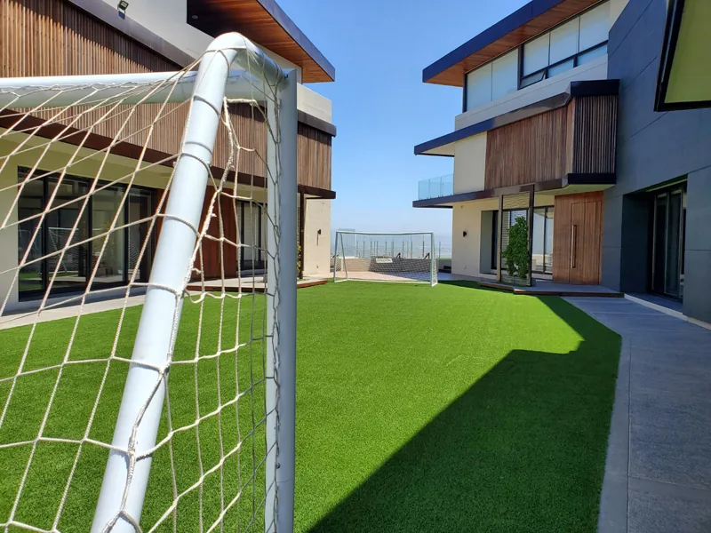 Portería de fútbol sobre pasto sintético en el jardín de una casa